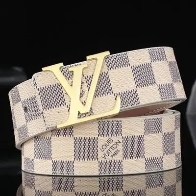 A pale checked-canvas belt coiled around a large gold buckle, photographed on black
