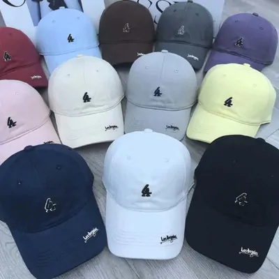 A pile of baseball caps in pastel and dark colours with small embroidered motifs