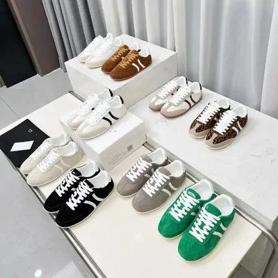 Low-top sneakers in brown, white, black, grey and green arranged on white shelving